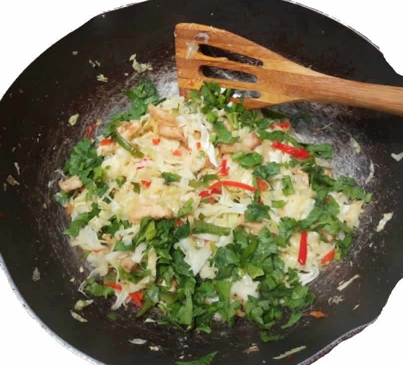fried cabbage in a sauce pan and a wooden spatula